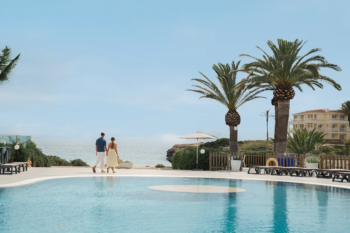 Pareja paseando junto a la piscina Hotel Fergus Style Carema Beach