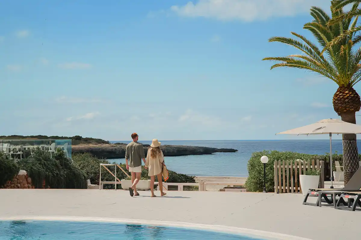 Pareja saliendo de la zona de piscina hacia la playa Fergus Style Carema Beach