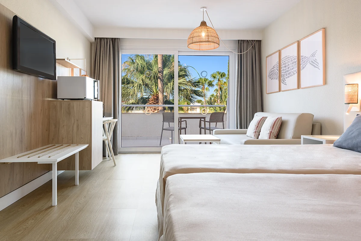 Habitación doble con sofá y vistas al jardín del Fergus Club Palmanova Park