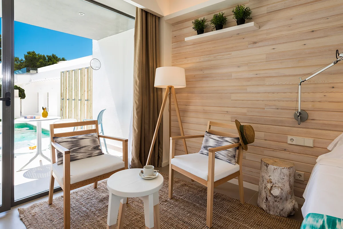 Pequeña zona de estar con butacas y mesa café en la habitación swim-up del Fergus Style Palmanova